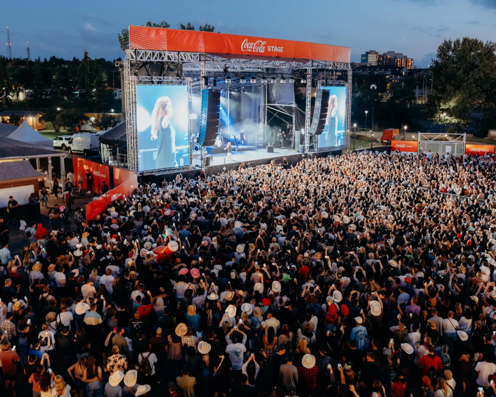 Festival artist performing onstage before a large sunset audience